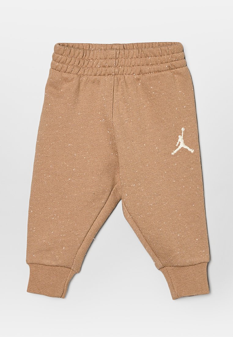 Pantalones de algodón marrón con cintura y puños elásticos, que cuentan con un acento de logo blanco en la pierna izquierda. Superficie texturizada con un patrón moteado.