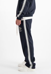 Navy joggerpants hebben witte zijstrepen en een logo-patch. Gemaakt van een zachte stof, hebben ze een elastische tailleband en een koorddetail.