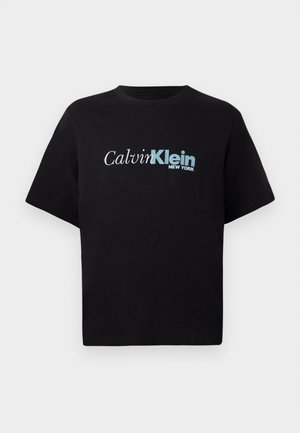 Czarna koszulka z krótkim rękawem z logo "Calvin Klein New York" w białym i niebieskim kolorze pośrodku klatki piersiowej na jednolitym tle.