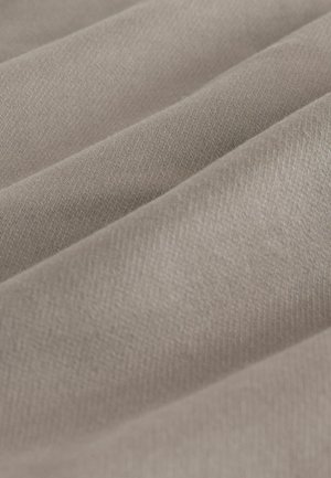 Nahaufnahme von weichem beigen Stoff mit sanften Falten und sichtbarer feiner Webstruktur.