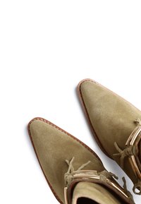 Botine din suede de culoare verde oliv, cu vârful ascuțit, garnituri din piele și accesorii decorative aurii, inclusiv sireturi.