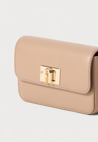 Borsa a mano in pelle beige con texture liscia, forma rettangolare, chiusura magnetica e accessori in tonalità oro.