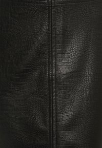 Černá texturovaná faux kůže s motivem ještěrky a vertikálním švem pro vyšší strukturu. Celkově hladký povrch.