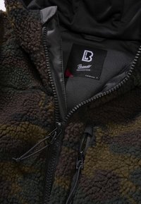 Fleece hooded jacket featuring a camouflage pattern in dark greens and browns. Includes a full zipper and two zippered pockets.