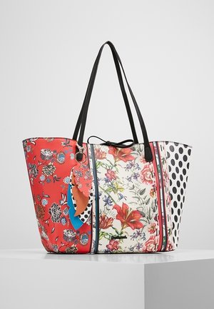 Torba na ramię z czarnymi uchwytami, ozdobiona czerwonymi kwiatami, białymi kwiatami oraz czarnymi kropkami na panelach, z warstwą dekoracyjnych zawieszek w kształcie liści.