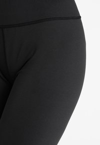 Czarne legginsy wykonane z elastycznego, gładkiego materiału. Posiadają bezszwowy pas oraz dopasowany krój, który idealnie przylega do ciała.