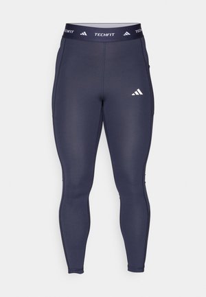 Marineblå tights laget av elastisk stoff, med en kontrasterende hvit "TECHFIT" logo og emblem på livet.