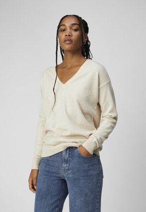 Lys beige v-hals sweater i blødt, strikket materiale med afslappet pasform og ribbede manchetter, parret med blå denim jeans.
