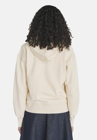 Felpa color crema con cappuccio regolabile, polsini e vita a costine, caratterizzata da una morbida texture e una vestibilità comoda.