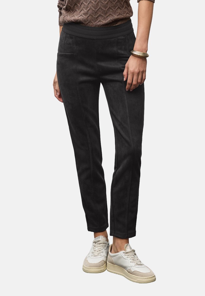 Svarta mockabyxor med slim fit, som har en bred midja, framfickor och sömdetaljer, i kombination med ljusa sneakers.