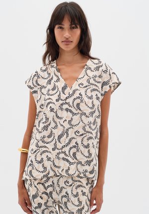 Short-sleeve blouse in cream fabric featuring a swirling black and beige pattern. V-neck design with a loose fit. Smooth texture.