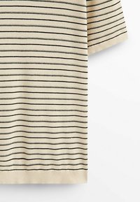 Chemise en tricot beige à manches courtes avec fines rayures horizontales noires et ourlet côtelé sur fond blanc uni.