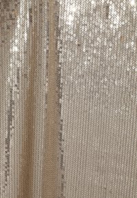 Tissu en sequins dorés avec des sequins circulaires disposés verticalement. La texture est brillante et réfléchissante, créant un effet visuel scintillant.