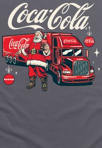 Coca-Cola Lkw-Grafik mit einem Weihnachtsmann, der eine Flasche hält. Rot-weiße Farbgestaltung mit Details wie Rädern, Sternen und einem Weihnachtsornament.