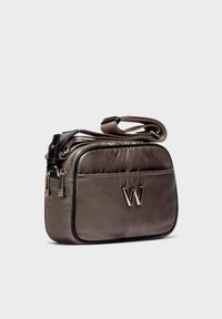 Pequeño bolso cruzado marrón acolchado con ribete negro, cierre de doble cremallera, bolsillo frontal y logotipo metálico "W" en el panel frontal.