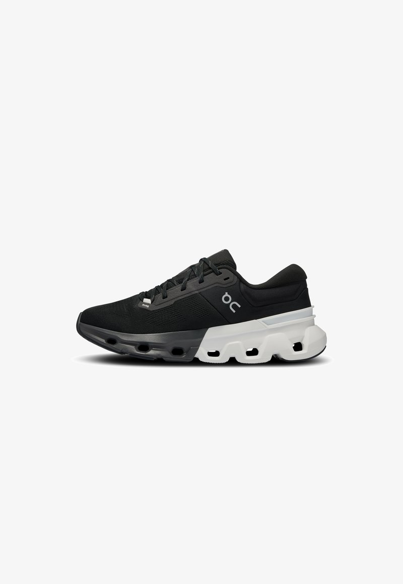 Baskets de sport noires avec un dessus texturé, des accents gris clair et une semelle distinctive avec des sections creusées pour un amorti.
