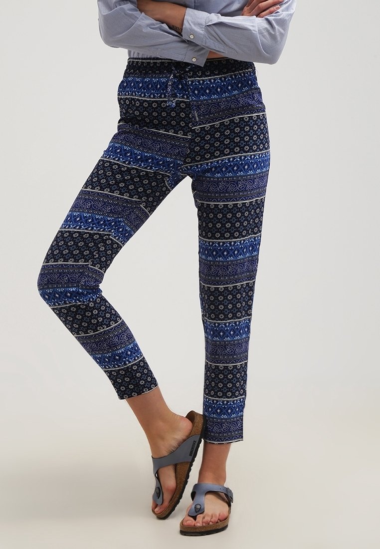 Blå mönstrade byxor med en blandning av ränder och blommönster, med resår i midjan och kort längd. Kombinerade med svarta sandaler.