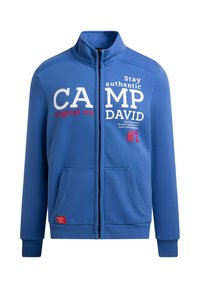 Blue zip-up sweatshirt made of soft fabric, featuring white and red text design. Includes front pockets and ribbed cuffs for comfort.