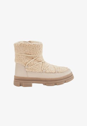 Botte d'hiver beige avec un dessus en shearling texturé et une base en cuir lisse. Présente une semelle épaisse et robuste et des lacets noués sur le devant.