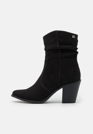 Mustat tekonahkasaappaat nilkkapituisena, joissa on löysä muotoilu, terävä kärki ja teksturoitu lohkare korko. Varustettu hienovaraisella ompelulla ja logo-yksityiskohdalla.