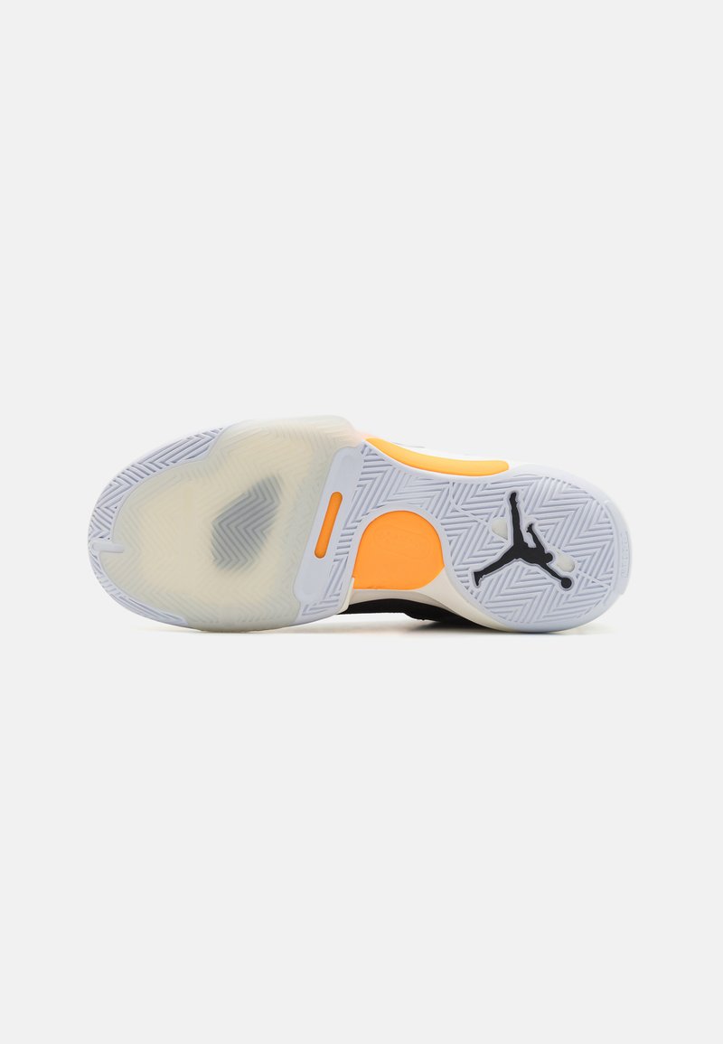 Suela de zapato de baloncesto negra con goma blanca, acento naranja, patrón texturizado de espiga y un prominente logo de Jumpman.