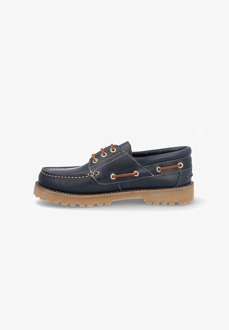 Zapato de barco de cuero azul marino con puntera redonda, suela de goma marrón, costuras en contraste y ojales marrones para los cordones. Diseño clásico de calzado sin cordones.