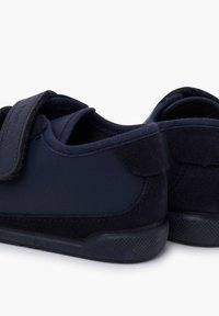 Tmavě modré boty vyrobené z kombinace hladkého syntetického materiálu a texturovaných semišových akcentů, se suchým zipem pro bezpečné upevnění.