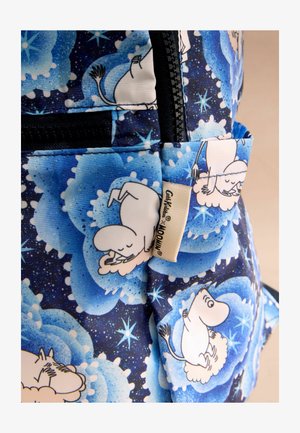 Sac à dos en tissu bleu avec un motif nuage comportant des personnages fantaisistes. Détail de fermeture éclair noir, petite étiquette sur le côté avec le logo du produit.