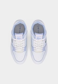 Ζευγάρι λευκών και ανοιχτό μπλε αθλητικών παπουτσιών Lacoste με κορδόνια, διάτρητες μύτες και λογότυπα κροκόδειλου στις πλευρές, εμφανιζόμενα από πάνω.