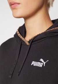 Hoodie noir avec une doublure en imprimé léopard dans la capuche, comportant un logo Puma blanc brodé à l'avant et un détail de cordon de serrage.