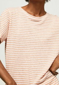 Stribet kortærmet t-shirt i blød bomuld, med skiftevis lyse orange og hvide striber, rund halsudskæring og afslappet pasform.