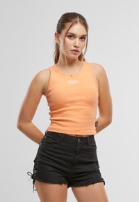 Appelsinribbete tank topp med rund halslinning, med en hvit logo på brystet; kombinert med svarte denimshorts med snøring på sidene.
