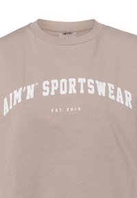 Light brown cotton t-shirt featuring a round neckline and white text that reads "AIM'N SPORTSWEAR EST. 2013" in a curved design.