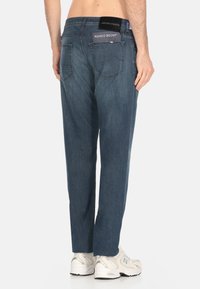Jeans in denim blu scuro con vestibilità a gamba dritta, caratterizzati da una vita media e tasche posteriori. Include etichette del marchio sulla vita.