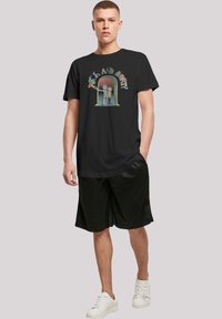 Černé bavlněné tričko s barevným grafikou "Rick a Morty". Krátké rukávy, kulatý výstřih. V kombinaci s černými kraťasy a bílými teniskami.