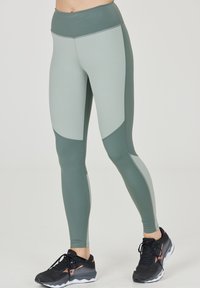 Höga leggings i en ljusgrön och mörkgrön färgblockdesign. Tillverkade av ett stretchigt material, med paneler och en jämn textur.
