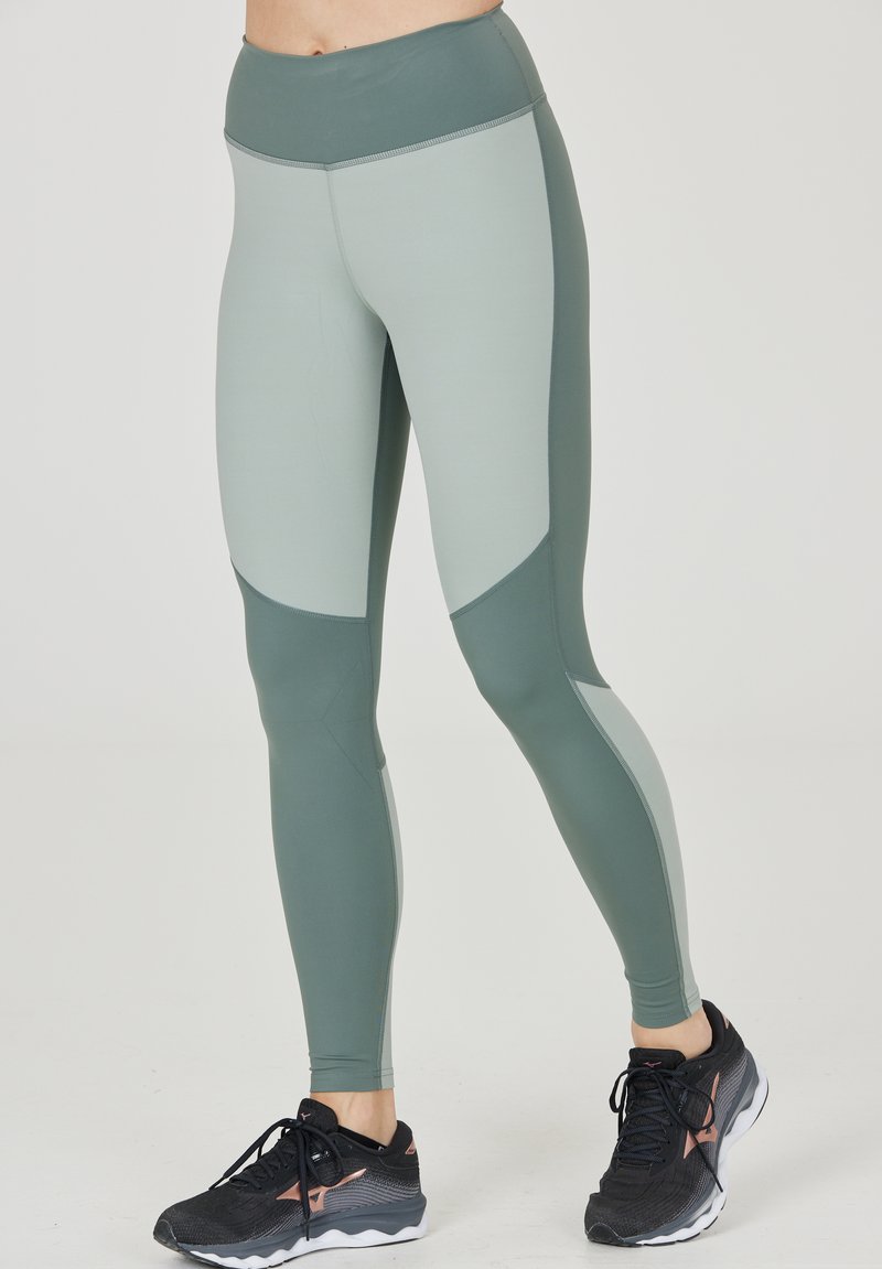 Höga leggings i en ljusgrön och mörkgrön färgblockdesign. Tillverkade av ett stretchigt material, med paneler och en jämn textur.