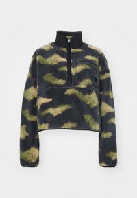 Skrócony polarowy pulower w kolorze granatowym z zielonym i beżowym wzorem w kamuflaż; wysoki kołnierz z zamkiem, kieszeń na piersi z logo, teksturowana powierzchnia.