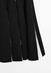 Black fabric skirt featuring side slits, raw edges, and a smooth texture. The design highlights a simple, flowing silhouette.