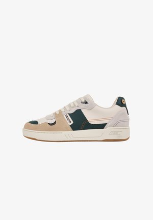 Sneakers met een mix van beige suède, groene leer en witte mesh, met een witte zool, oranje stiksels en een logo op de zijkant.