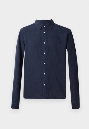 Camisa de manga larga navy con cuello abotonado, que presenta una tela texturizada y botones blancos en la parte delantera. Dobladillo inferior recto.