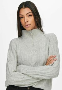 Light gray high-neck sweater with ribbed texture, cable knit patterns, and a half zipper featuring a silver ring pull.