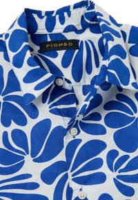 Camisa de manga corta, abotonada, con un patrón floral azul sobre un fondo blanco; fabricada en una tela ligera; cuenta con un collar clásico y un dobladillo redondeado.
