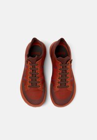 Röda och bruna sportskor med en strukturerad ovandel, kontrasterande snören och blå accenter, med en gummisula och vadderad krage.