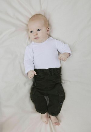 Body a maniche lunghe bianche e pantaloni cargo verde scuro con tasche, posati su una superficie di colore chiaro. I pantaloni hanno una vita regolabile con cordino.