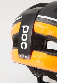 Casco POC arancione con una banda nera opaca, aperture di ventilazione e luci LED posteriori. Include etichetta di misura e sistema di cinturino regolabile.