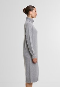 Graues gestricktes Rollkragenkleid mit gerippten Ärmelbündchen und Saum, das eine lockere Passform hat und bis zur Mitte der Wade reicht. Weiche Textur, minimalistisches Design.