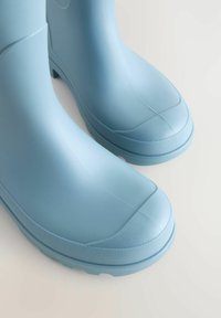 Világoskék gumicsizmák sima felülettel, lekerekített orral, mintás talppal és magas fazonnal. Nincsenek látható minták vagy fémalkatrészek.