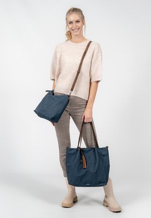 Navy blue textile bags with brown straps; one is a small crossbody, the other a larger tote with a tassel detail on the zipper.
