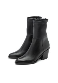 Botas negras hasta el tobillo hechas de cuero texturizado con un cierre zipper visible, punta afilada y un tacón grueso. Incluye un detalle de parte superior doblada.